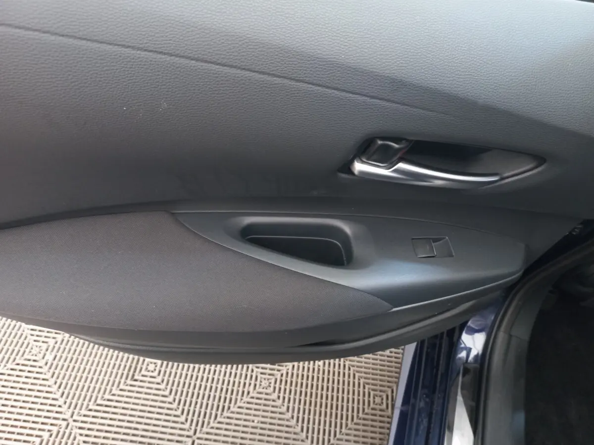 Vue rapprochée de la porte avant droite intérieure de la Toyota Corolla hybride bleu 2022 avec poignée argentée.