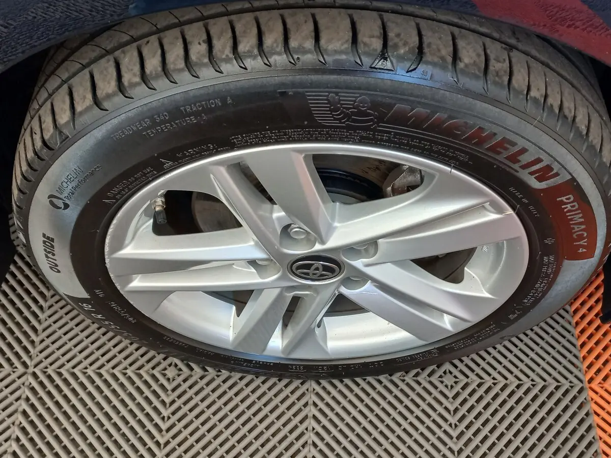 Gros plan sur la jante alliage argentée et pneu Michelin d'une Toyota Corolla hybride bleue.