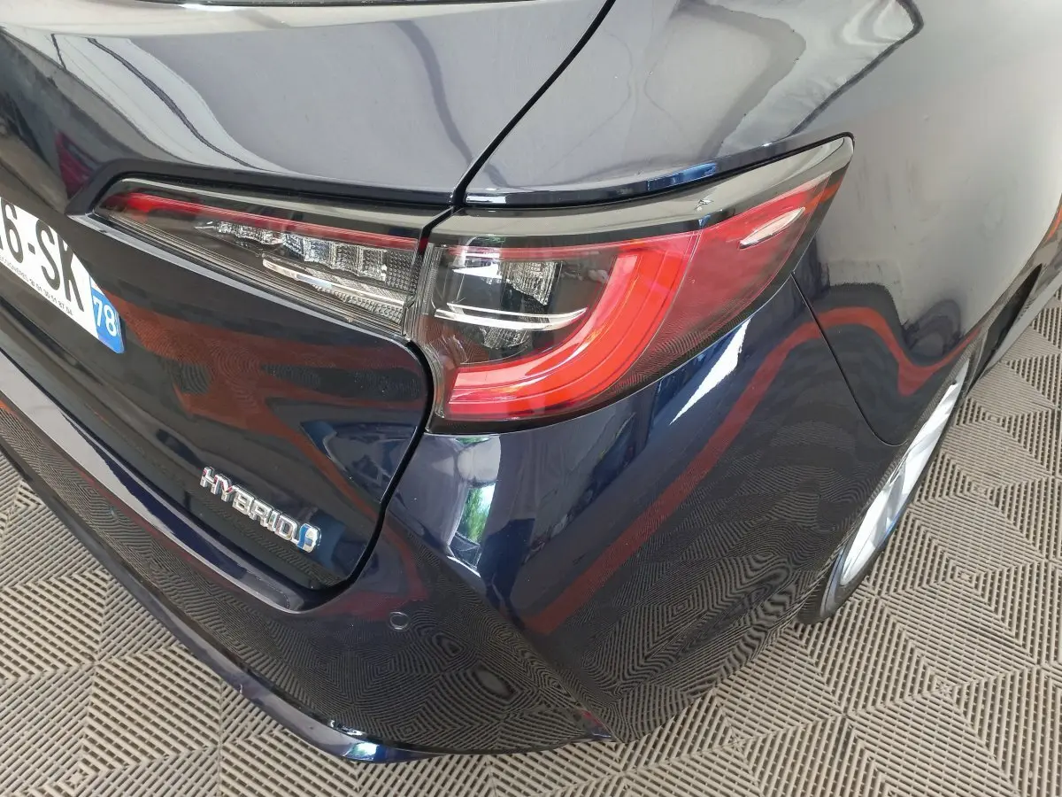 Vue arrière droite de la Toyota Corolla hybride bleu foncé, mettant en valeur le feu arrière et le badge Hybrid.