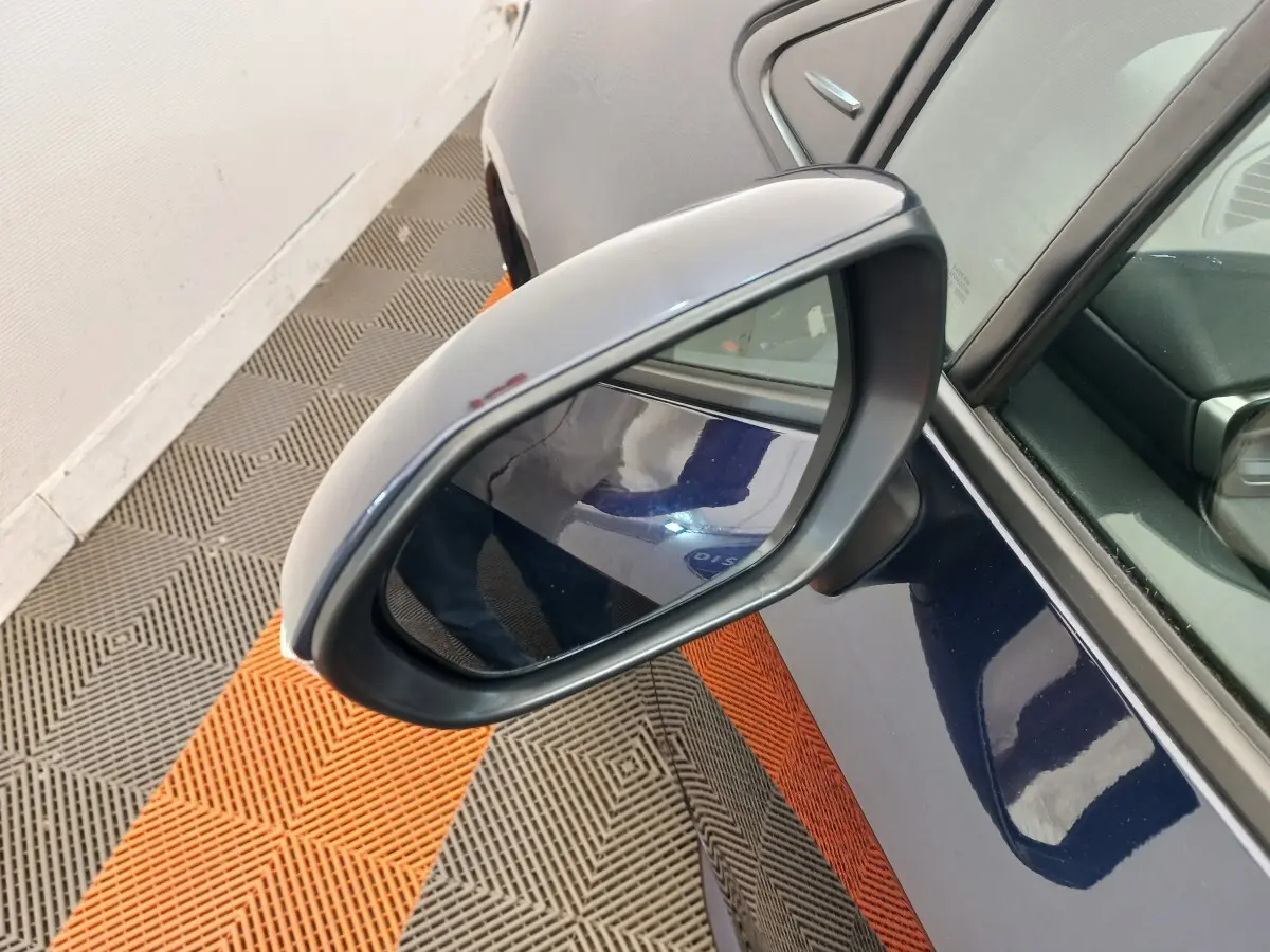Rétroviseur côté gauche d'une Toyota Corolla hybride bleu, avec partie de la portière visible en intérieur lumineux.