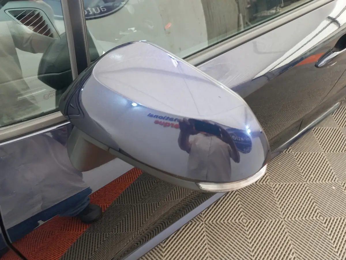 Rétroviseur côté gauche bleu brillant de la Toyota Corolla Hybride 2022 avec clignotant intégré, vue rapprochée.