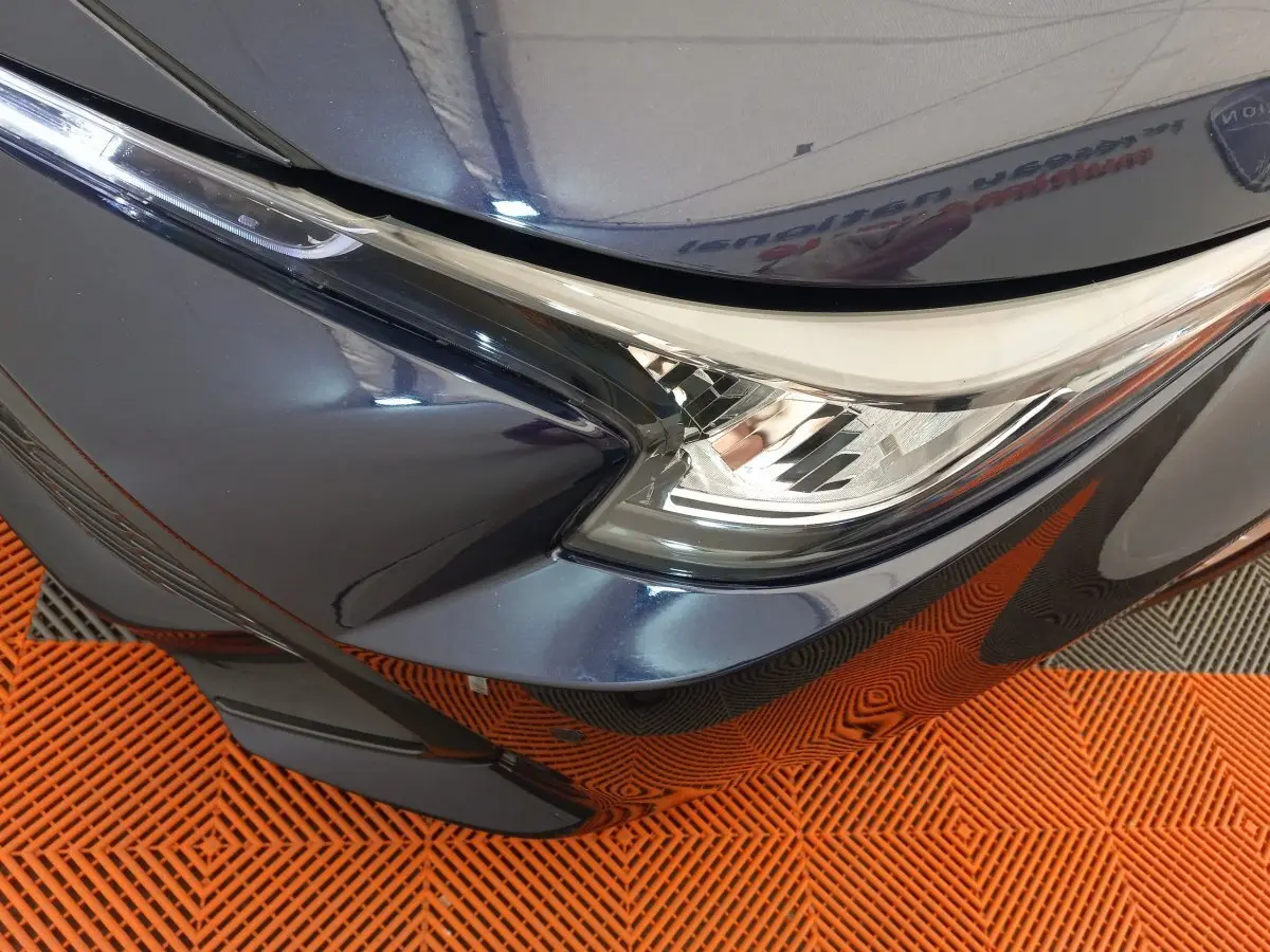 Gros plan sur le phare avant droit bleu métallisé de la Toyota Corolla Hybride 2022 avec détails du pare-chocs et calandre.