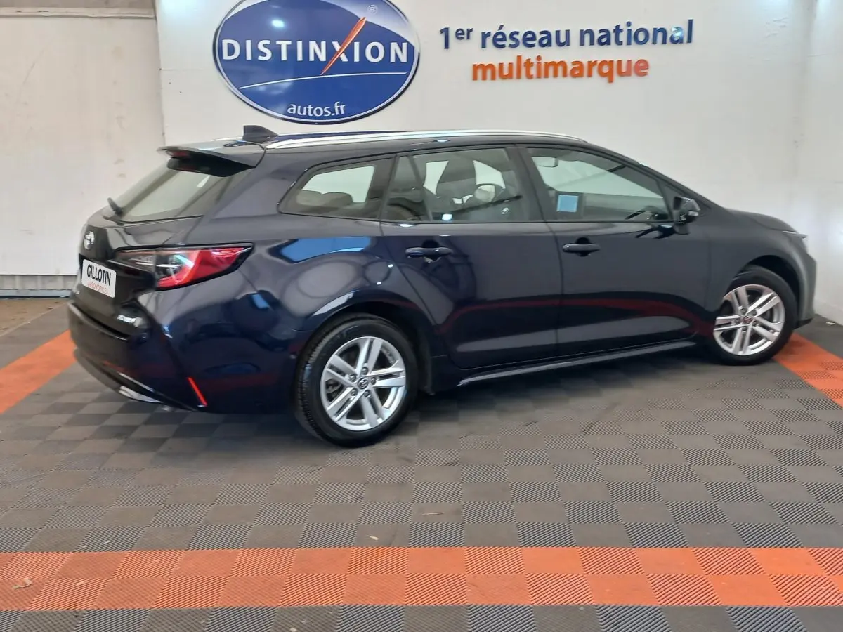 Toyota Corolla Hybride 122h bleu en vue latérale droite, break avec jantes alliage et toit noir contrasté.