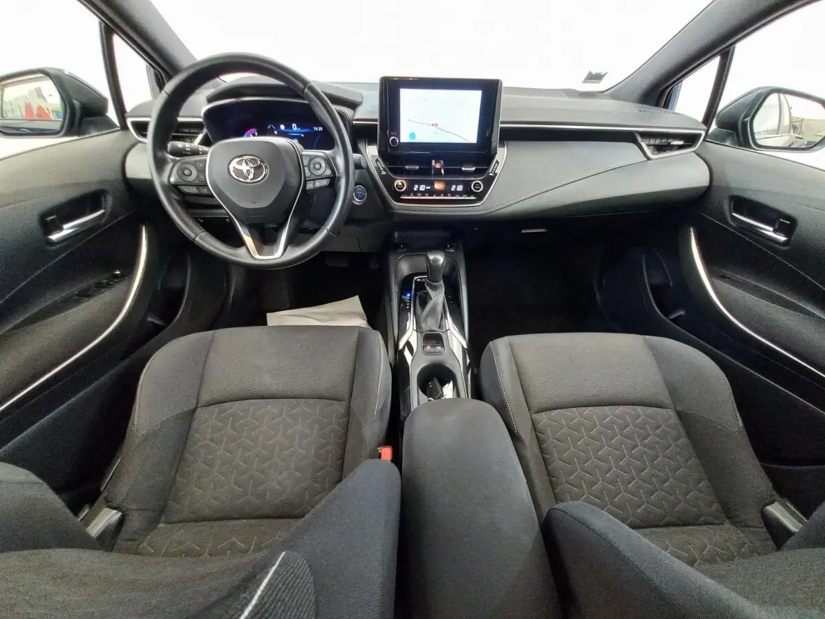 Vue intérieure avant de la Toyota Corolla hybride 2022, tableau de bord moderne avec écran tactile central et volant multifonctions cuir.