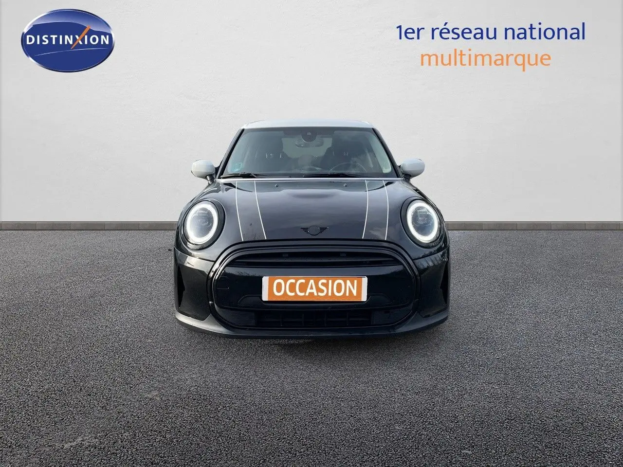 Vue frontale d'une MINI noire Midnight Metal avec bandes blanches sur le capot et rétroviseurs blancs.