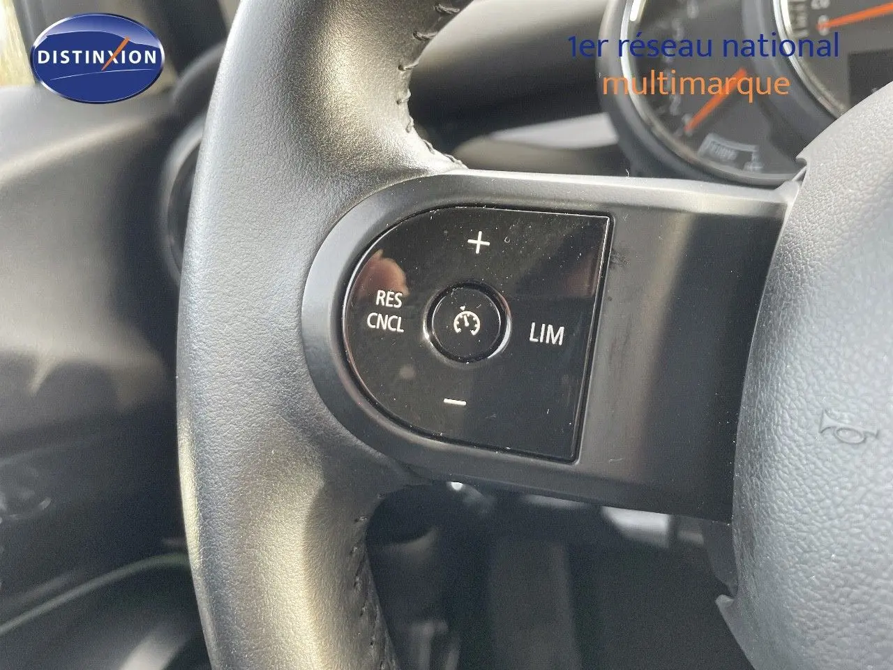 Gros plan sur le volant noir de la MINI 2023, mettant en valeur les commandes de régulateur de vitesse.