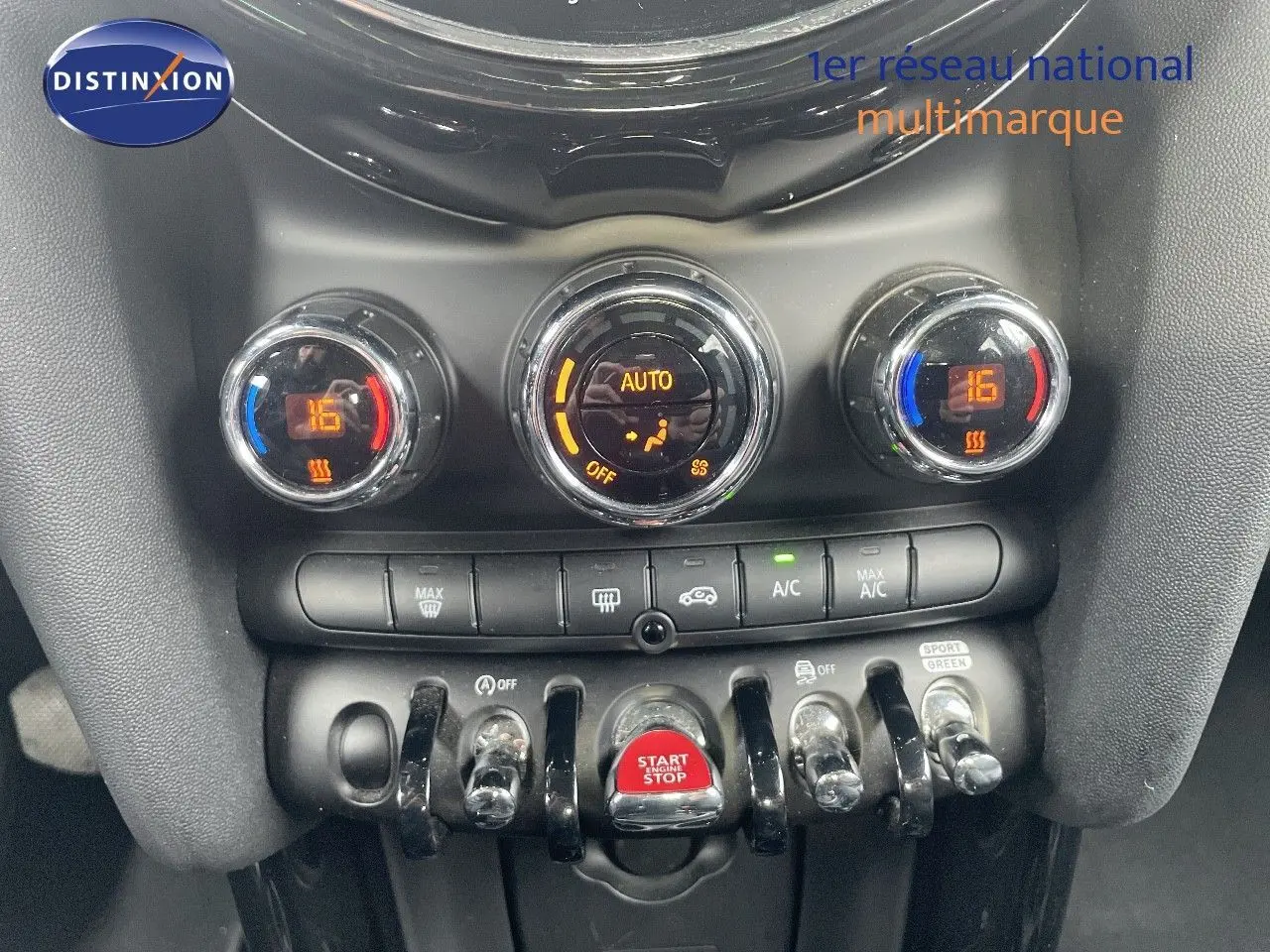 Gros plan sur la console centrale de la MINI 2023, avec commandes de climatisation et bouton start/stop rouge.