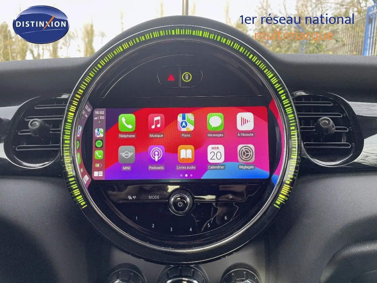 Vue rapprochée de l’écran tactile central rond du tableau de bord d’une MINI noire, avec interface Apple CarPlay affichée.