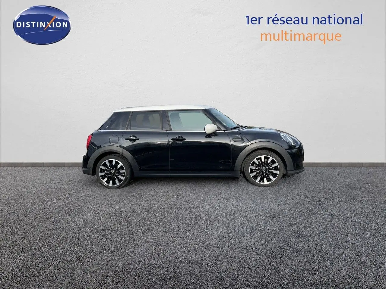 Vue de profil droit d'une MINI 1.5 136CH noire Midnight Metal avec toit blanc et jantes bi-ton, sur fond neutre.
