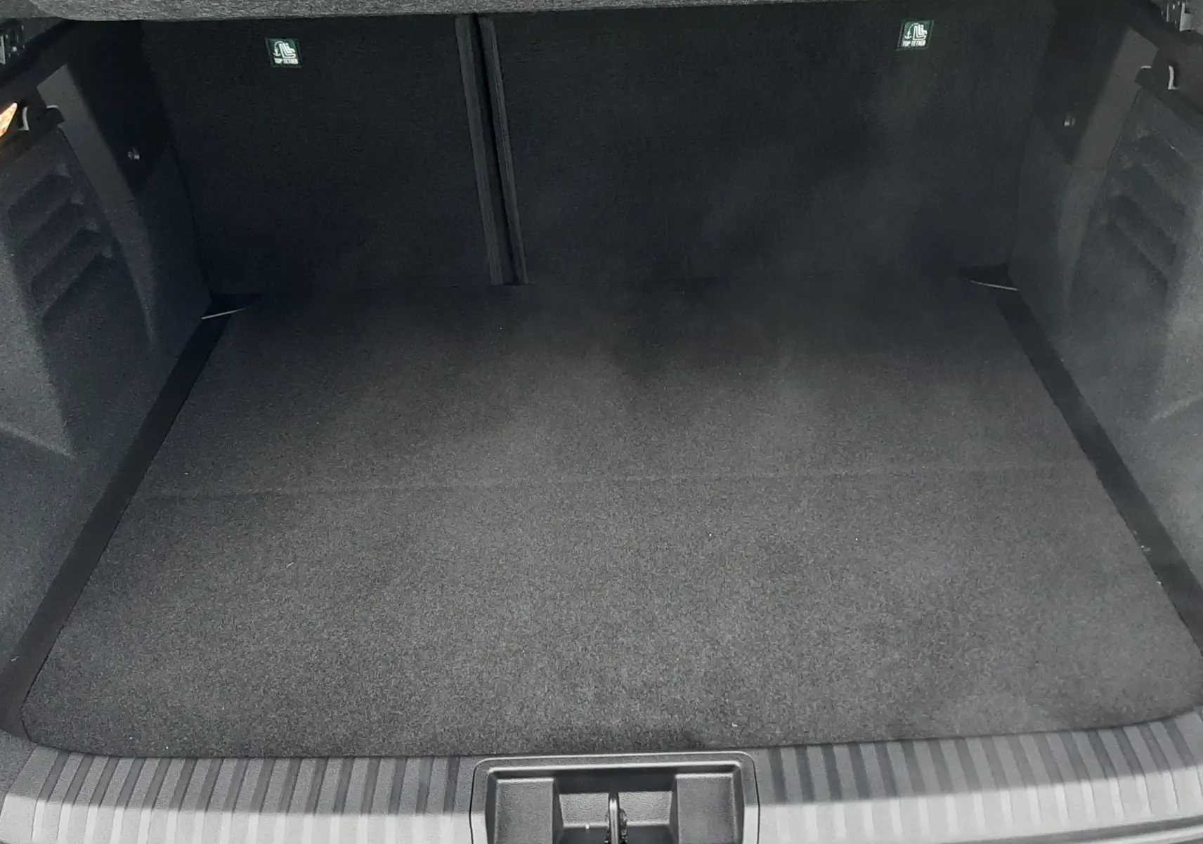 Vue plongeante sur le coffre vide d’une Renault Symbioz blanc nacré, soulignant son espace de rangement.