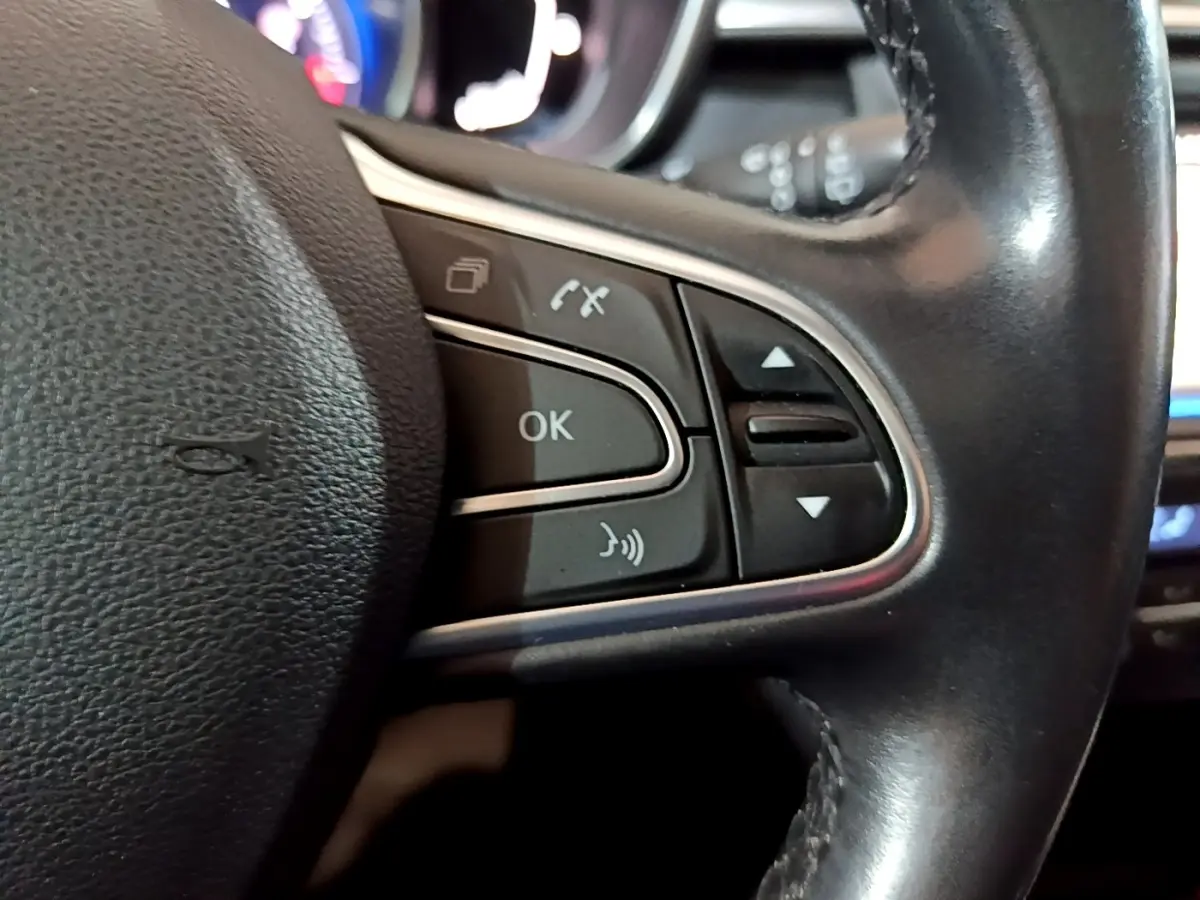 Gros plan sur les commandes multifonctions du volant cuir du Renault Kadjar Intens noir, avec boutons de navigation et téléphone.