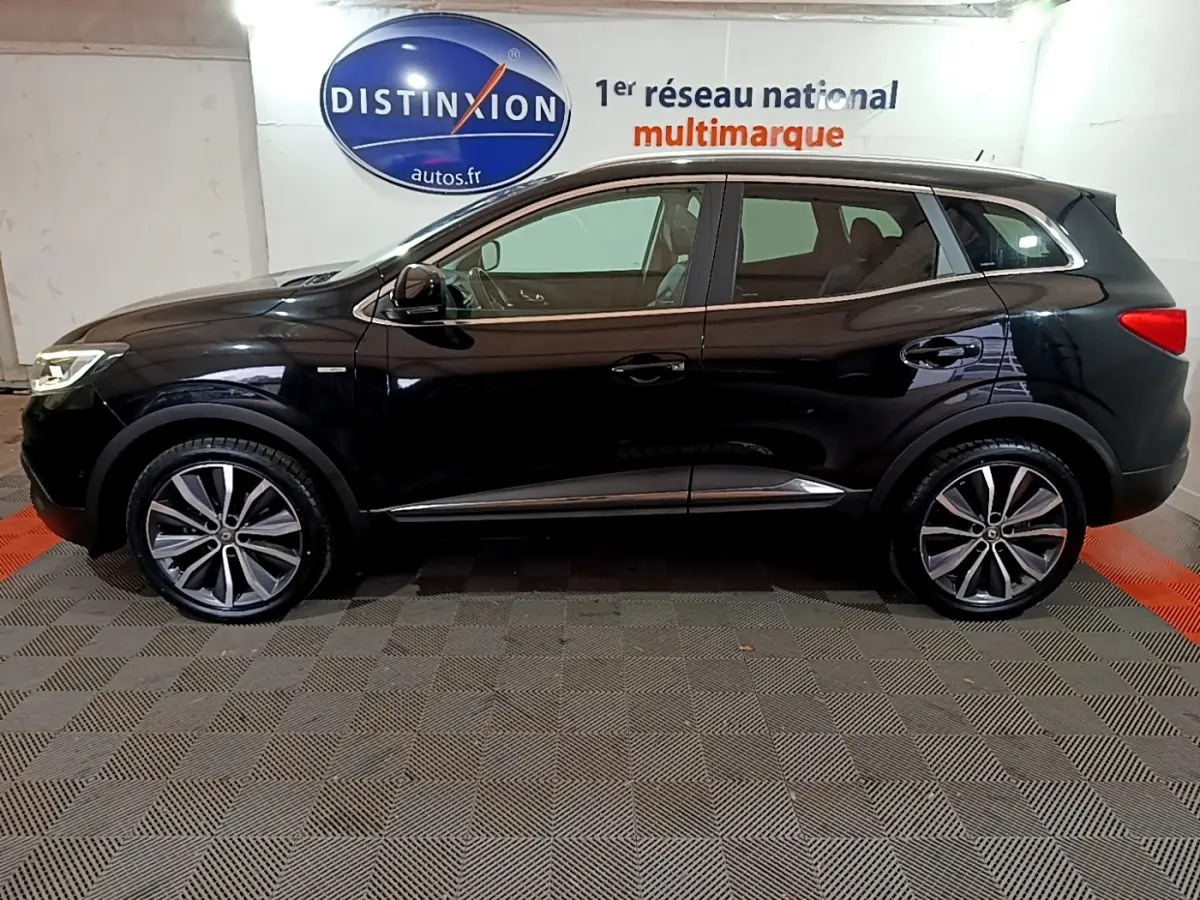 Profil côté gauche du Renault Kadjar noir 2018 avec jantes alliage et vitres teintées en intérieur showroom.