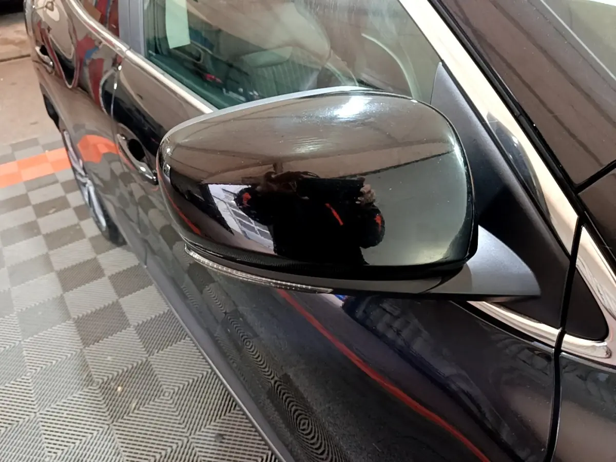 Rétroviseur côté gauche noir brillant du Renault Kadjar Intens Energy TCe 130, vue rapprochée sur la portière noire.