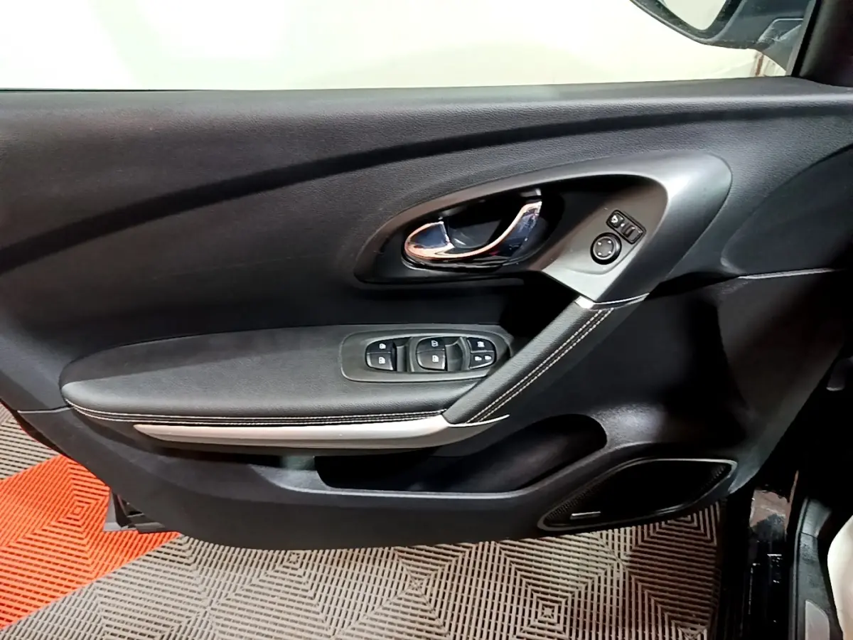 Vue rapprochée de la porte avant gauche noire du Renault Kadjar Intens avec commandes de vitres et poignée chromée.