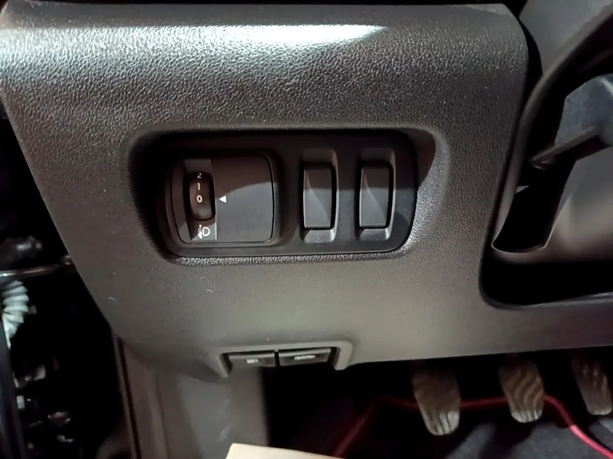 Gros plan sur les commandes d'éclairage et réglages sous le tableau de bord du Renault Kadjar noir 2018 côté conducteur.