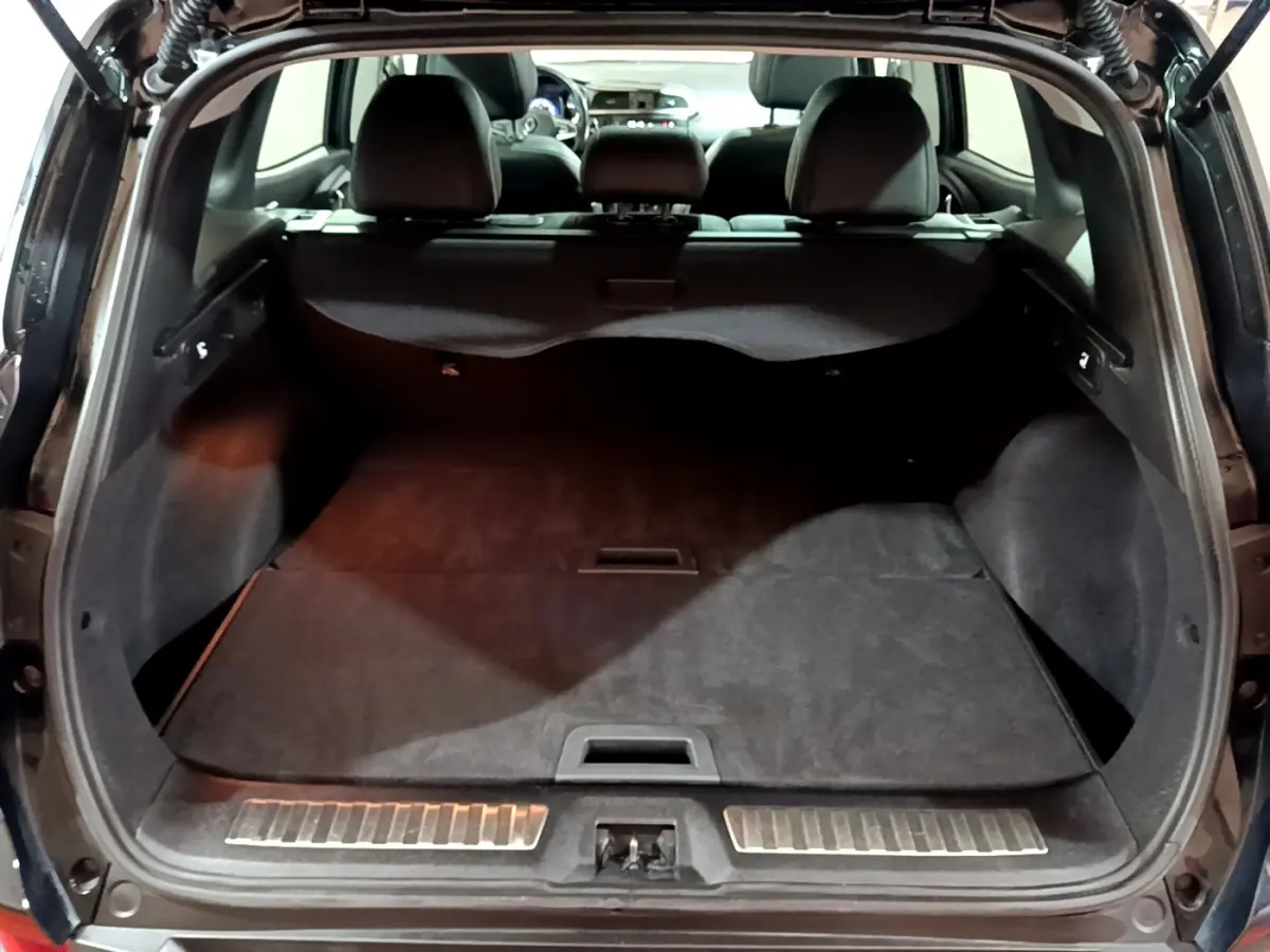 Coffre ouvert du Renault Kadjar Intens noir, vue arrière montrant l'espace de chargement et la banquette rabattue.