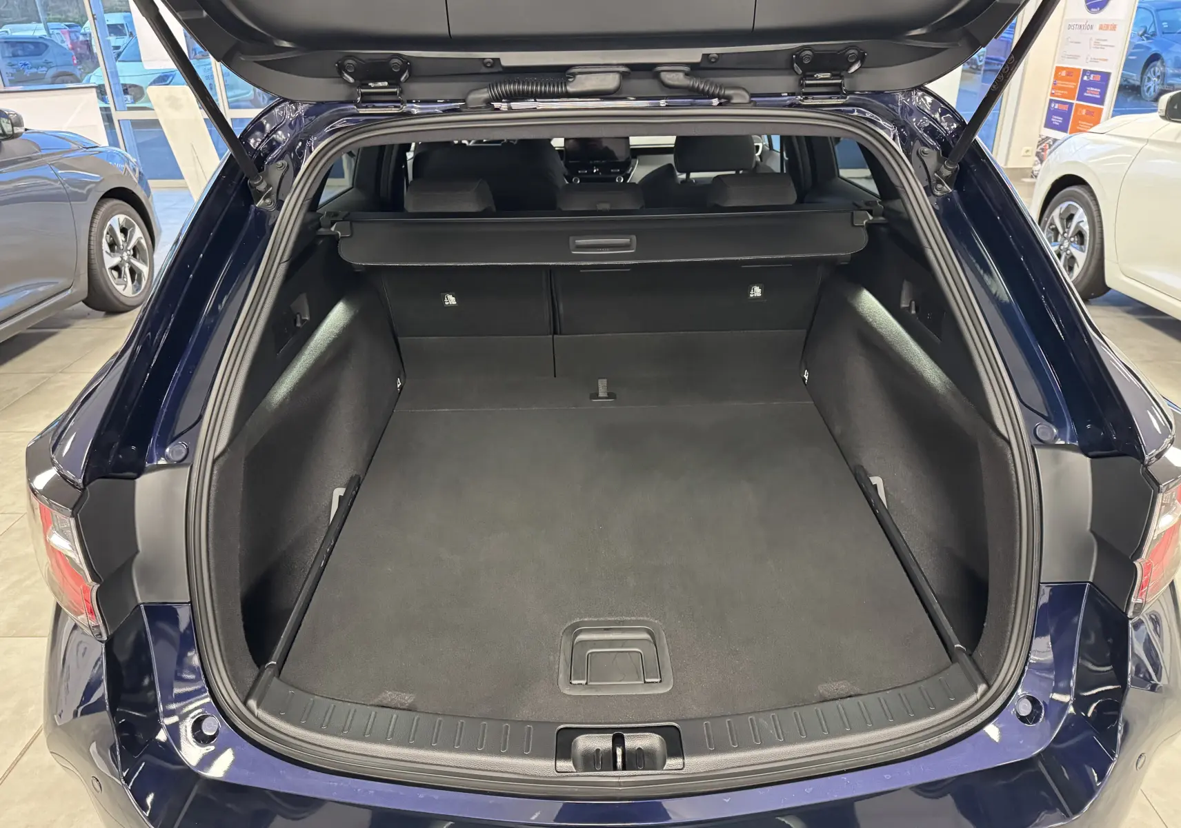 Coffre ouvert en vue arrière d’une Suzuki Swace bleue 2025, montrant un espace de chargement spacieux et propre.