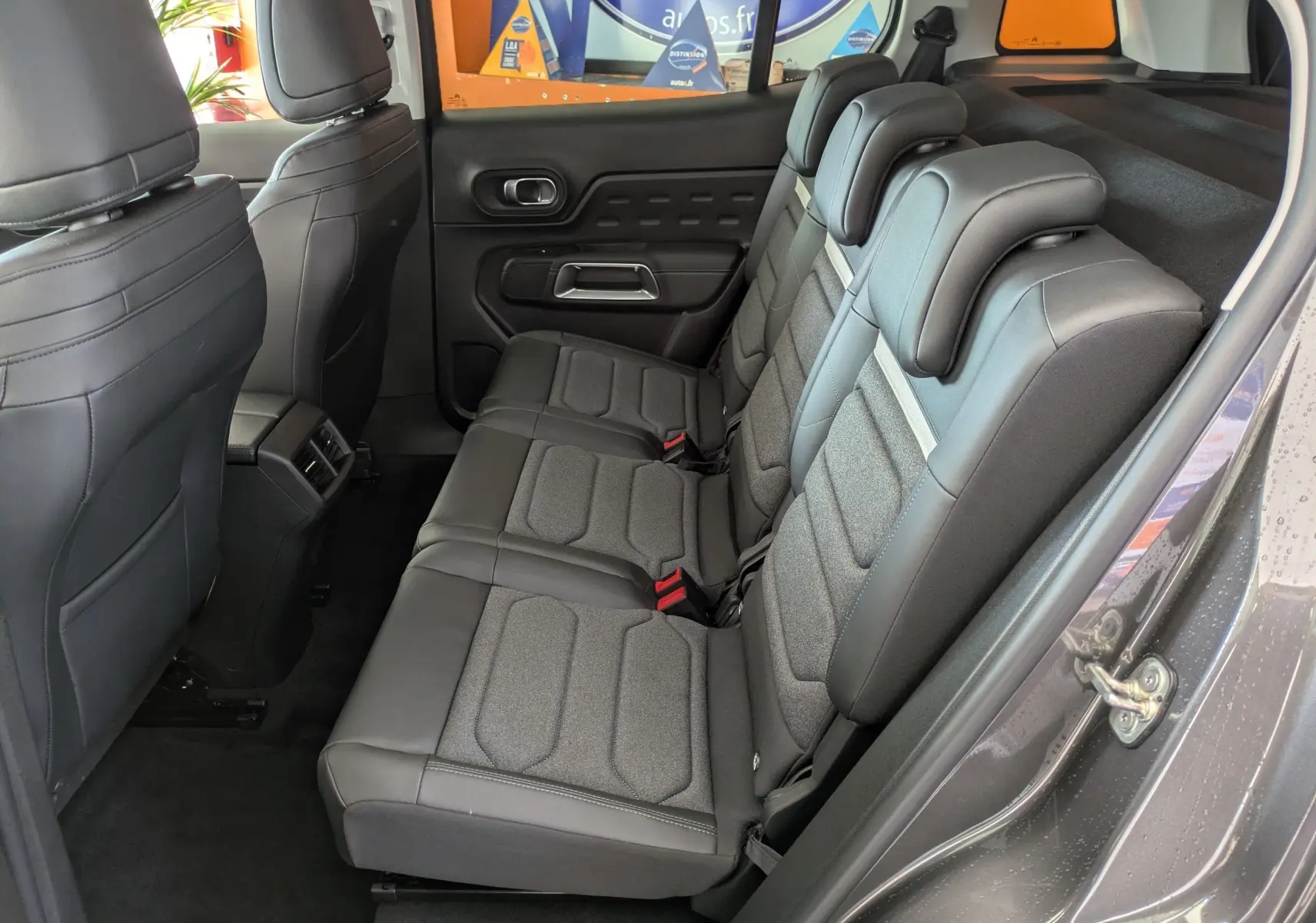 Vue intérieure côté droit montrant la banquette arrière en tissu et cuir du Citroën C5 Aircross Hybride gris platinium 2025.