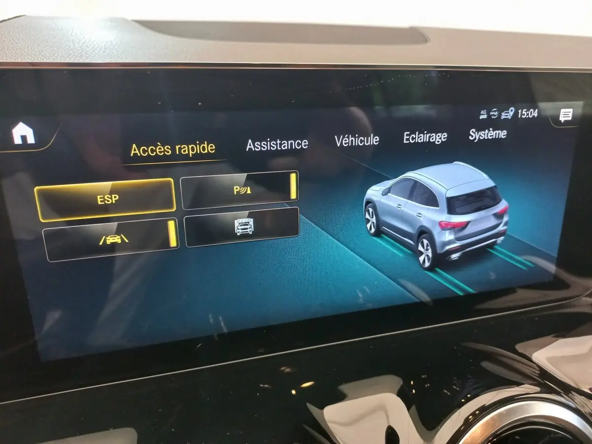 Écran tactile intérieur montrant l'interface d'assistance avec une voiture grise vue en 3/4 arrière.
