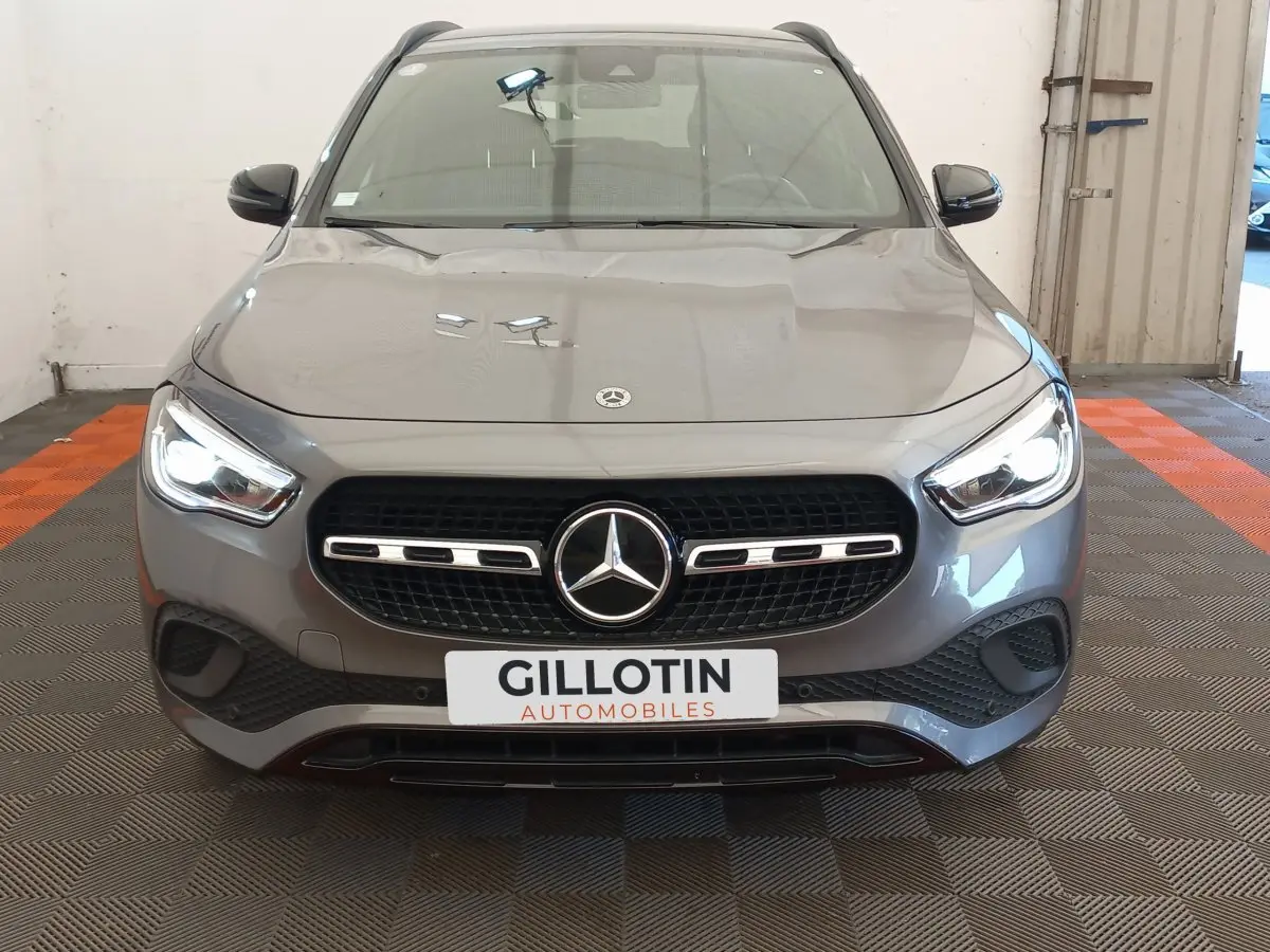 Vue frontale d'une Mercedes GLA 200 Business Line gris foncé avec phares LED allumés en intérieur showroom.