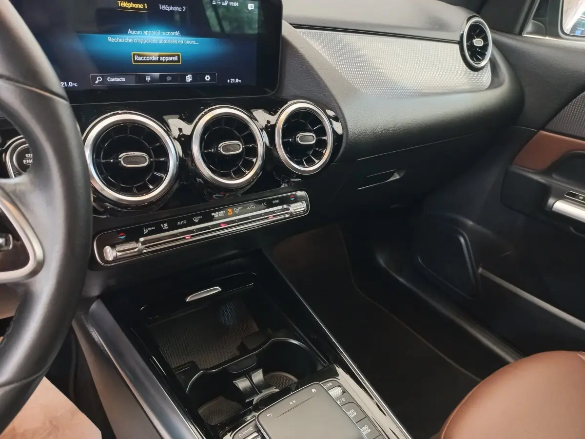 Vue intérieure côté passager du tableau de bord noir et brun du Mercedes GLA 200 Business Line avec écran tactile et aérateurs ronds.