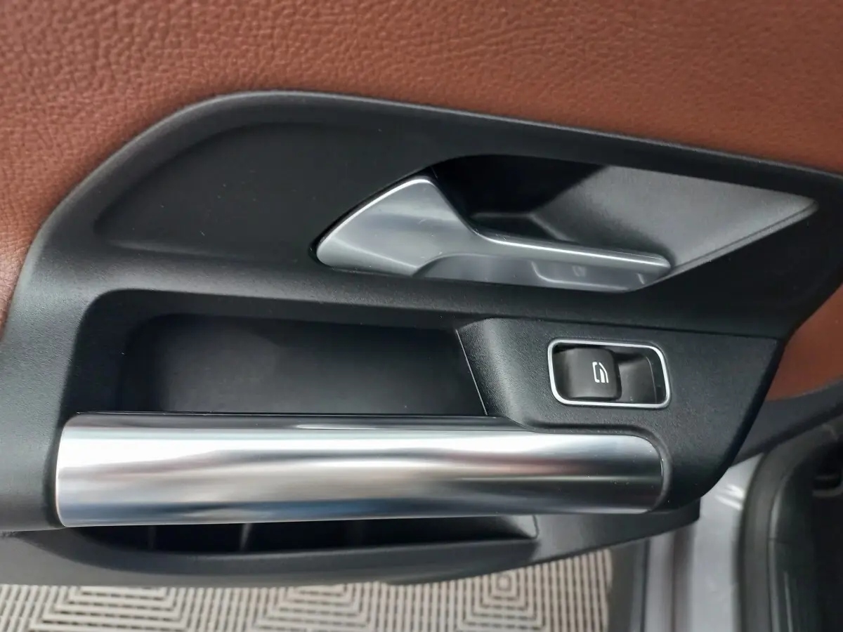 Poignée intérieure de porte avant droite en métal brossé et plastique noir sur Mercedes GLA gris foncé, 2021.
