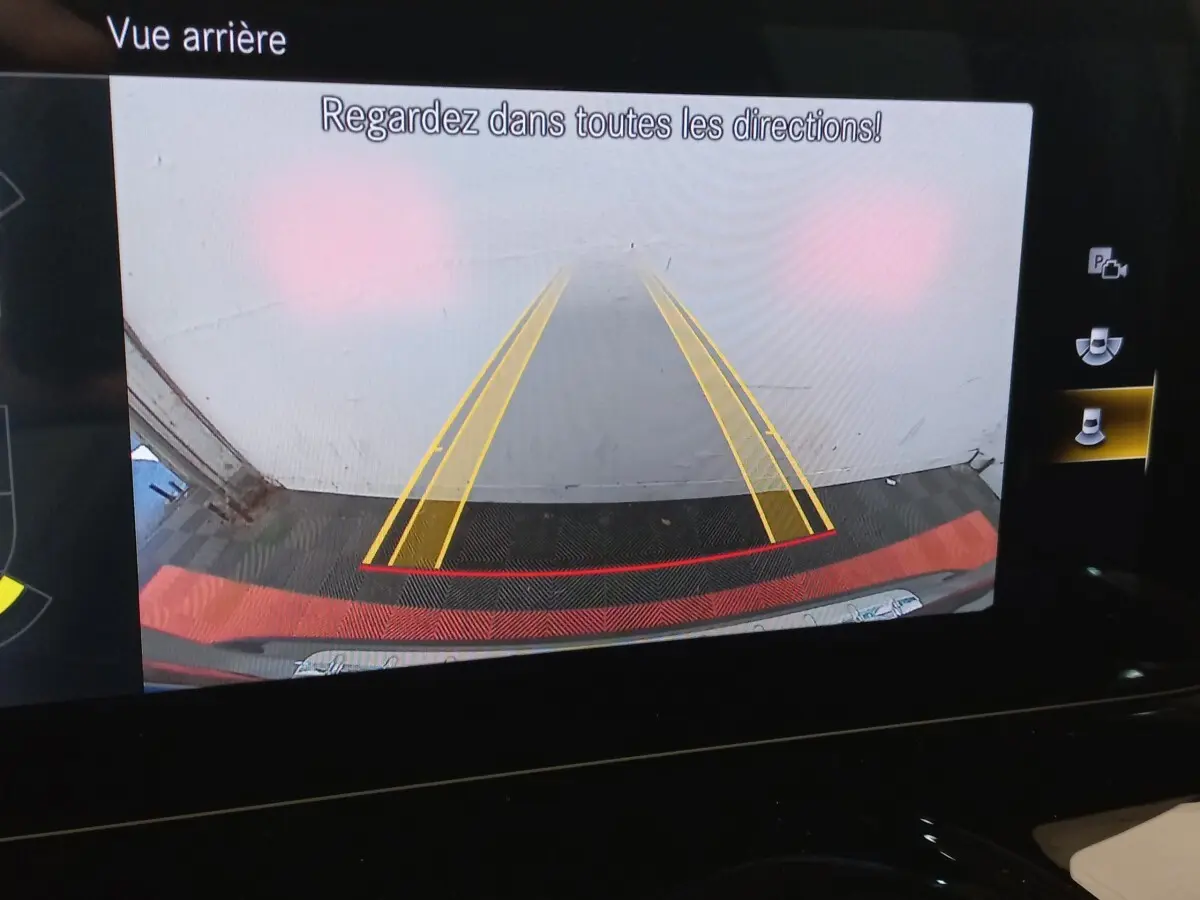 Affichage de la caméra de recul du Mercedes GLA 200 gris foncé, avec lignes de guidage jaunes et rouges visibles.
