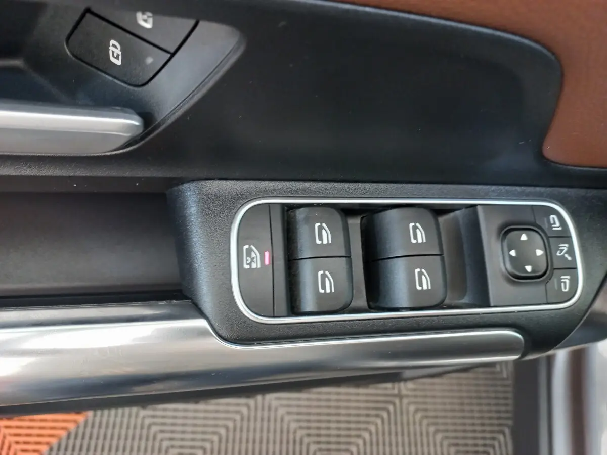 Gros plan sur les commandes de lève-vitres et rétroviseurs côté conducteur d’une Mercedes GLA 200 gris foncé.