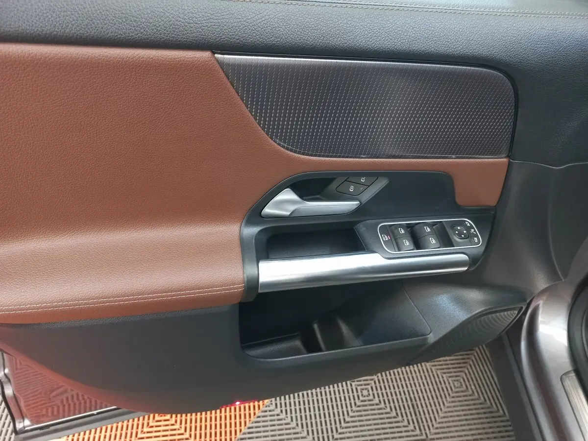 Vue rapprochée de la porte avant gauche du Mercedes GLA 200 Business Line 2021, avec garniture marron et commandes électriques.