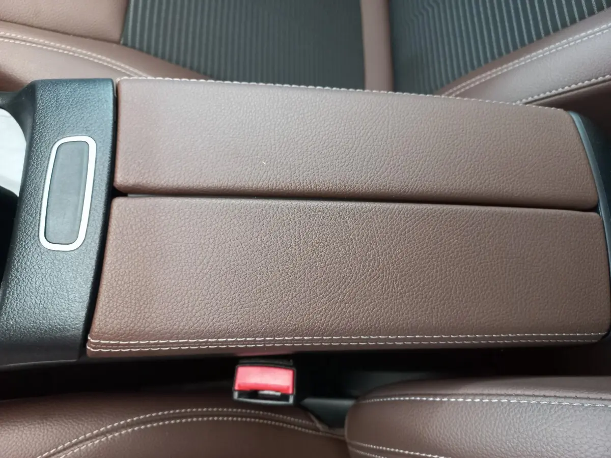 Gros plan sur l'accoudoir central en cuir marron avec surpiqûres blanches dans l'habitacle du Mercedes GLA 200.
