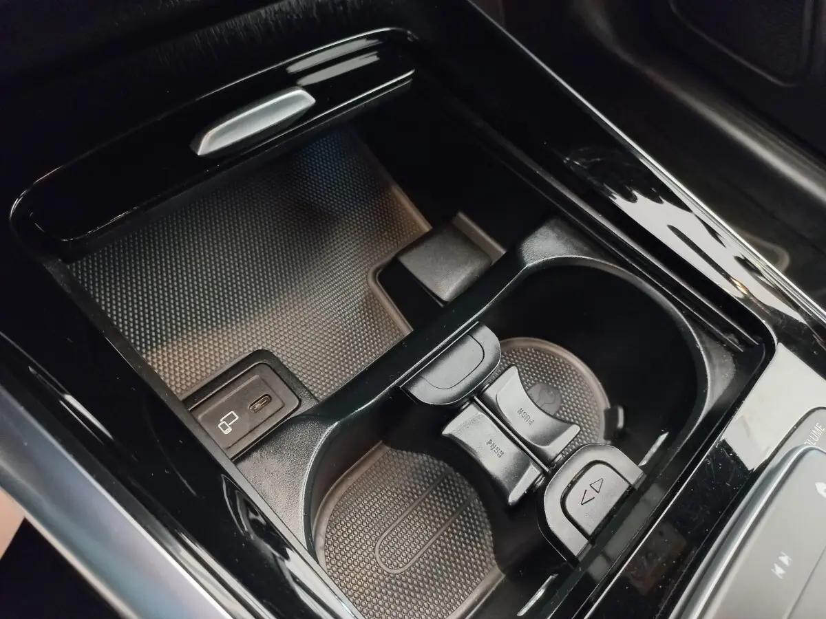 Gros plan sur la console centrale noire brillante avec porte-gobelets et port USB de la Mercedes GLA 200 Business Line.