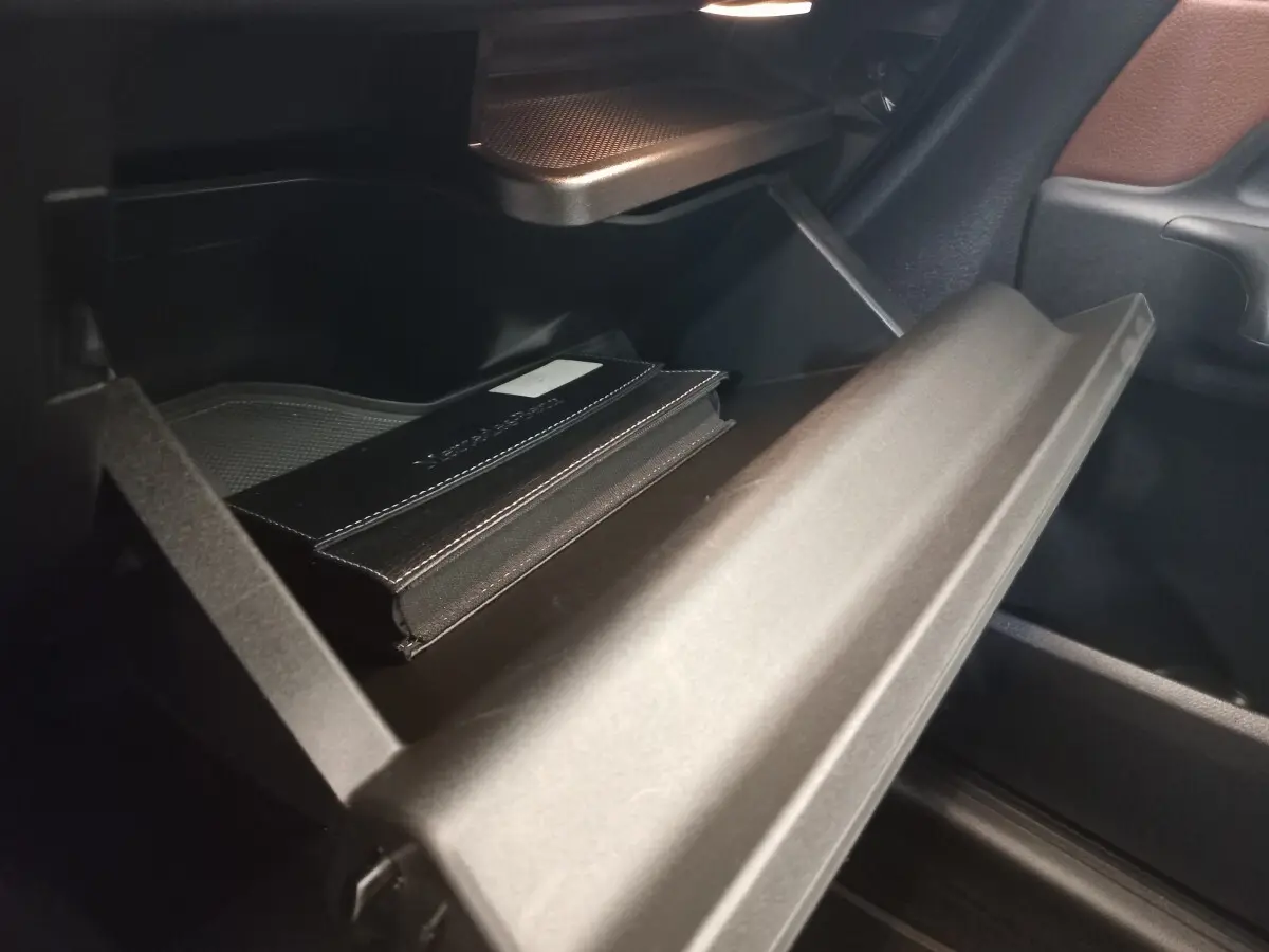 Gros plan sur la boîte à gants ouverte de la Mercedes GLA 200 Business Line 2021, avec un carnet noir à l'intérieur.