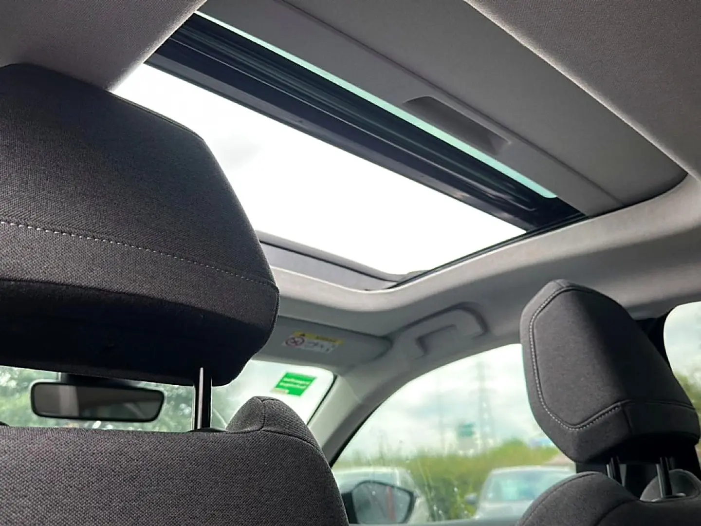 Vue intérieure arrière montrant les appuie-têtes noirs et le toit ouvrant panoramique du Citroën C4 gris 2024.
