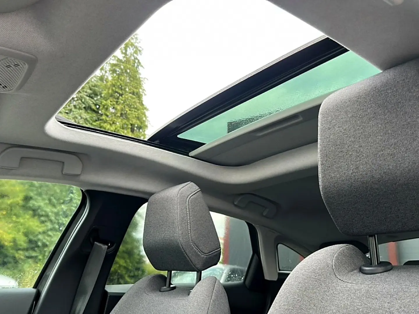 Vue intérieure sur les sièges avant gris et le toit ouvrant panoramique partiellement ouvert du Citroën C4 2024.