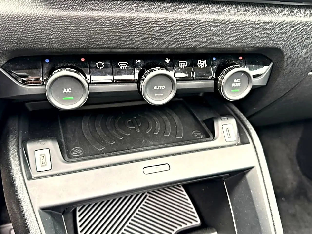 Détail de la console centrale noire avec commandes de climatisation automatique et recharge sans fil dans une Citroën C4 gris 2024.