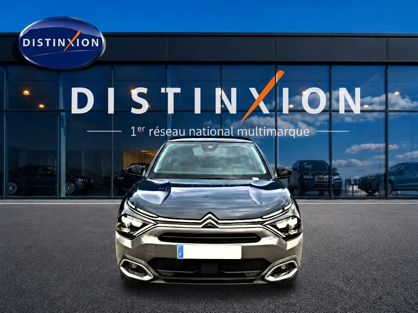 Citroën C4 1.5 BlueHDi 130 gris vue de face devant une vitrine avec logo Distinxion.