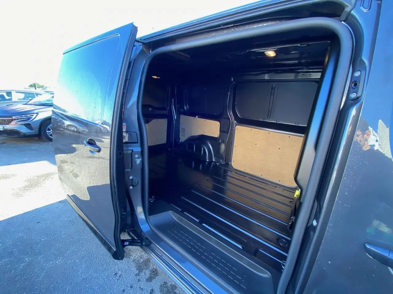 Vue latérale droite du Peugeot Expert Fourgon gris titane avec porte coulissante ouverte montrant l'espace de chargement vide.