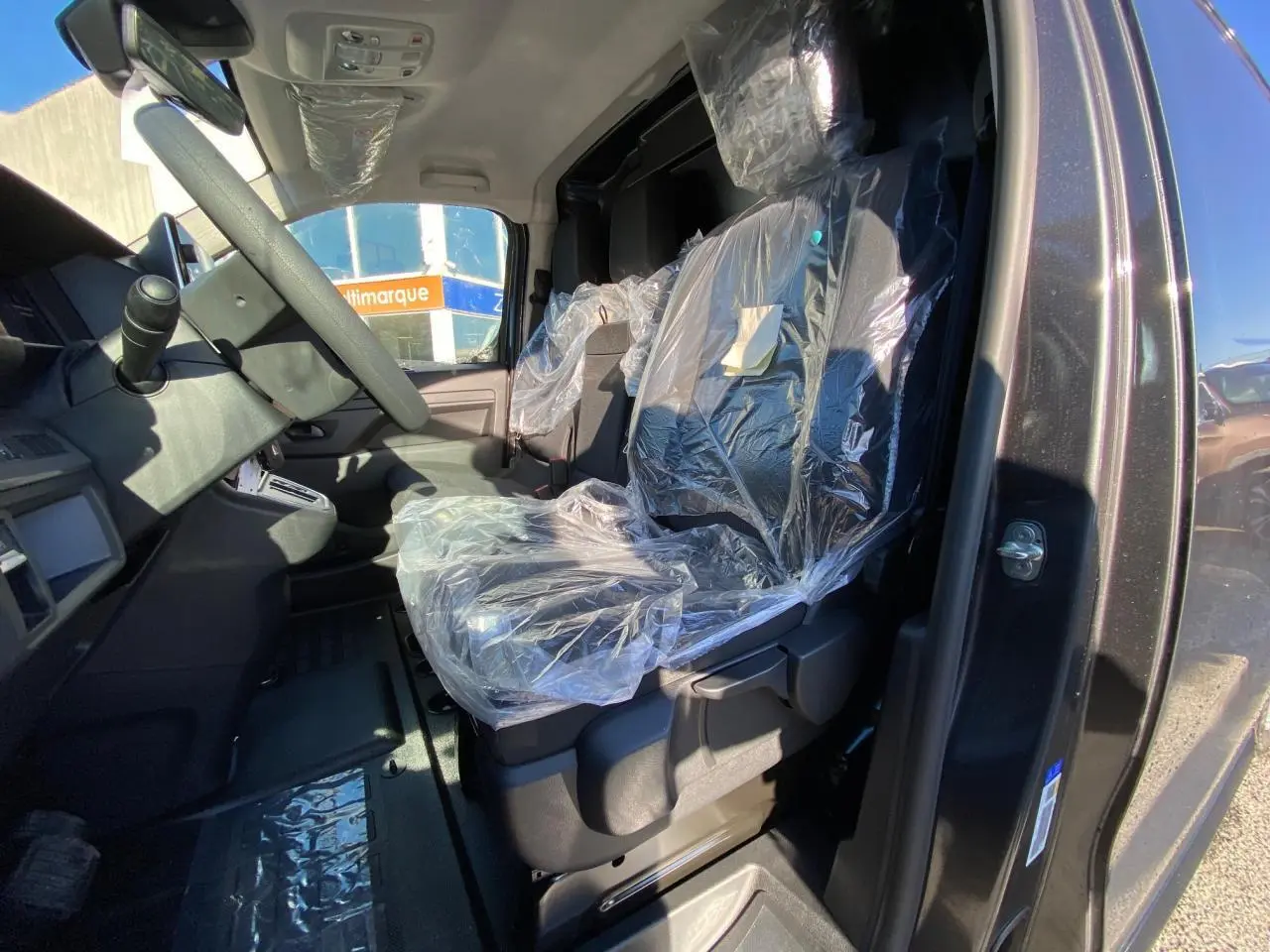 Vue intérieure côté conducteur du Peugeot Expert Fourgon gris titane, sièges protégés par film plastique.