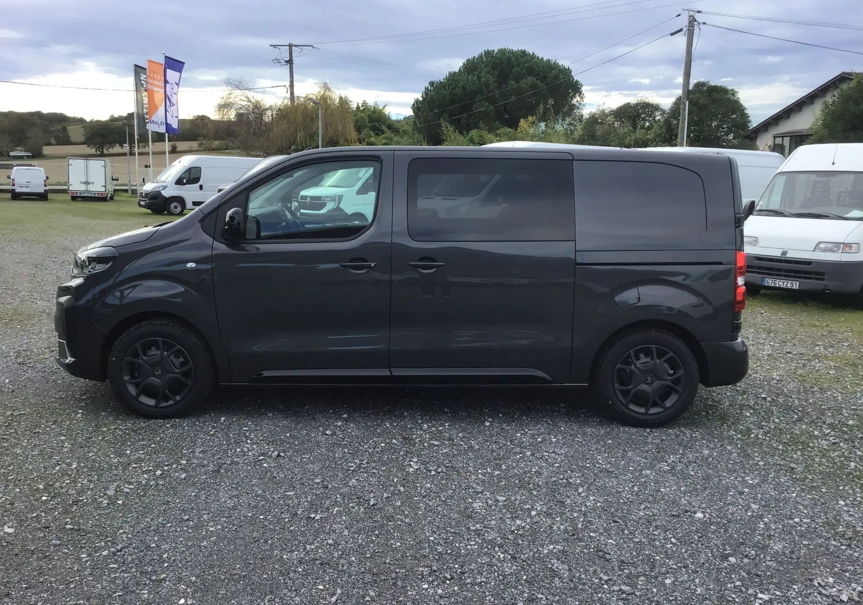 Profil côté gauche d'un Citroën Jumpy cabine approfondie gris titane avec vitres arrière teintées et jantes noires.