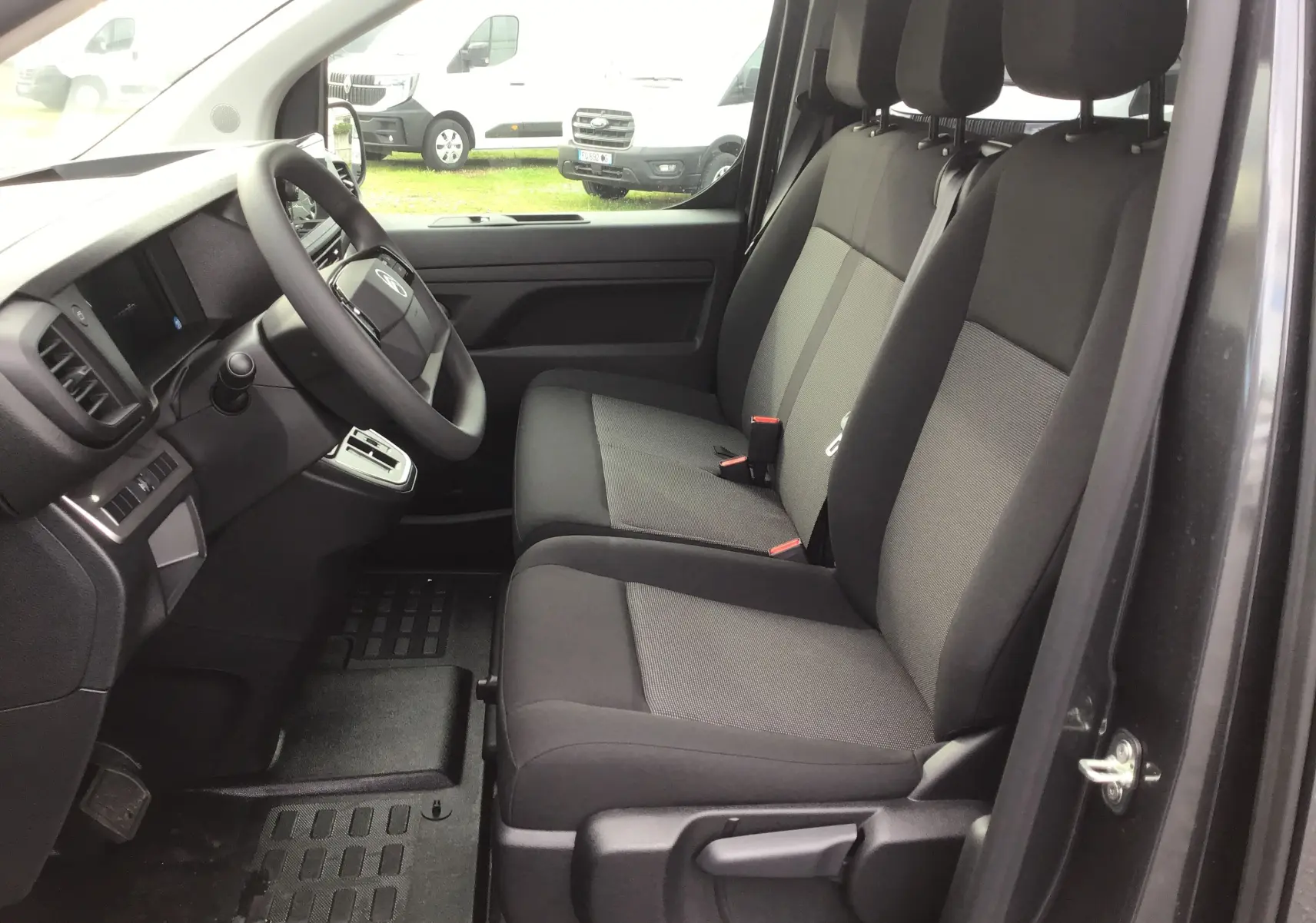 Intérieur côté conducteur du Citroën Jumpy gris titane, montrant les sièges avant et le tableau de bord moderne.