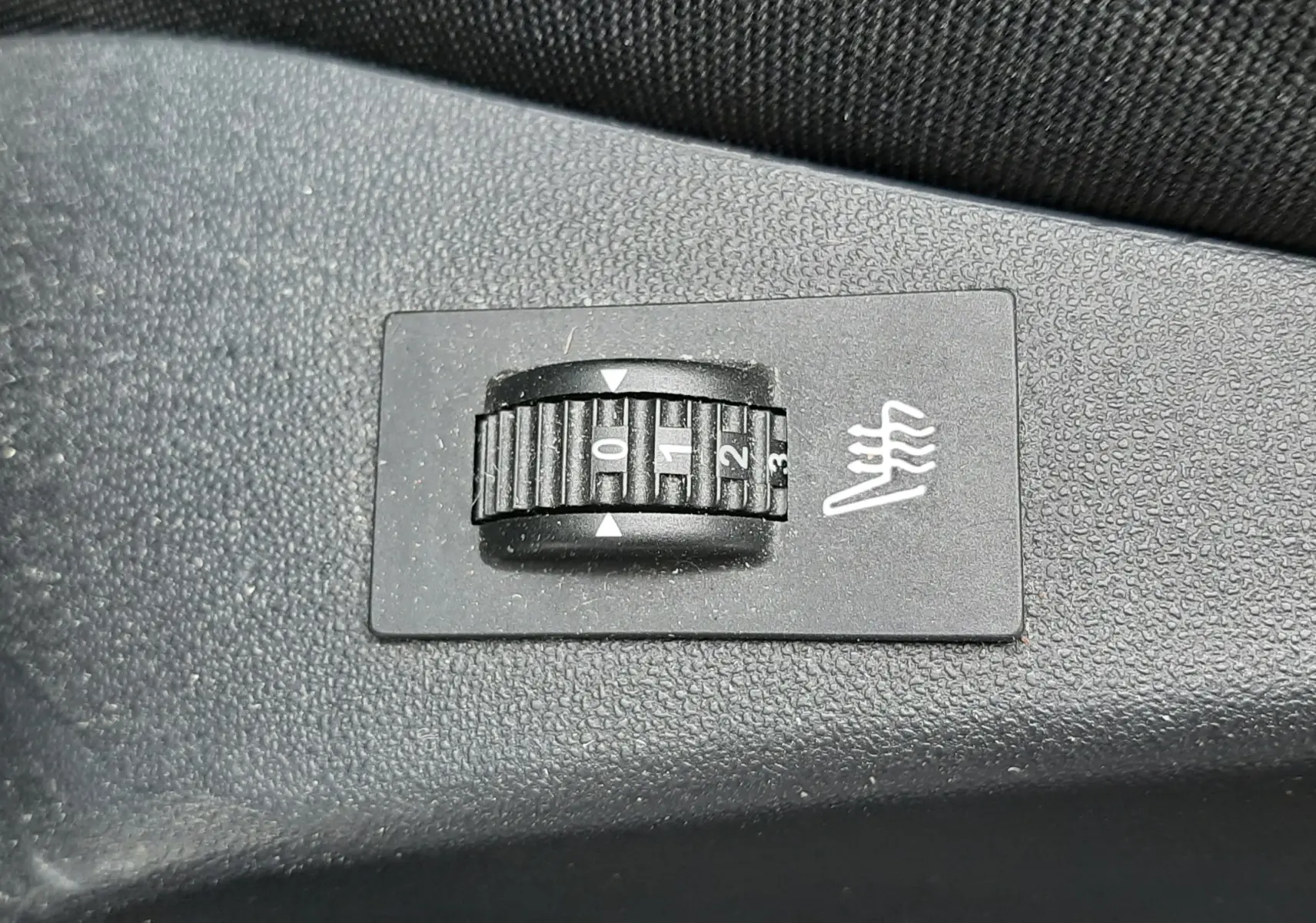 Réglage du chauffage de siège en gros plan sur une commande noire dans l'habitacle du Peugeot 2008 blanc de 2017