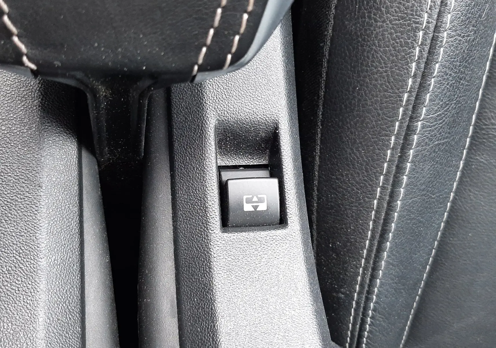 Bouton de commande de lève-vitre électrique sur la console centrale en cuir noir du Peugeot 2008 blanc de 2017.
