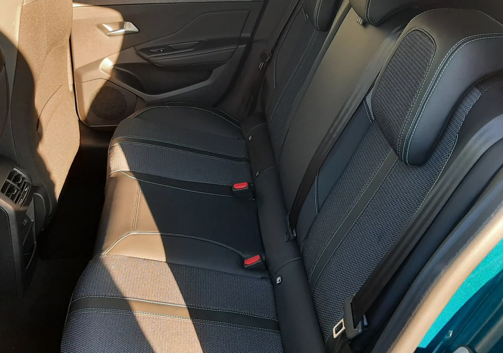 Vue intérieure côté droit des sièges arrière en tissu et cuir noir avec surpiqûres vertes d'une Peugeot 308 Bleu Obsession 2025