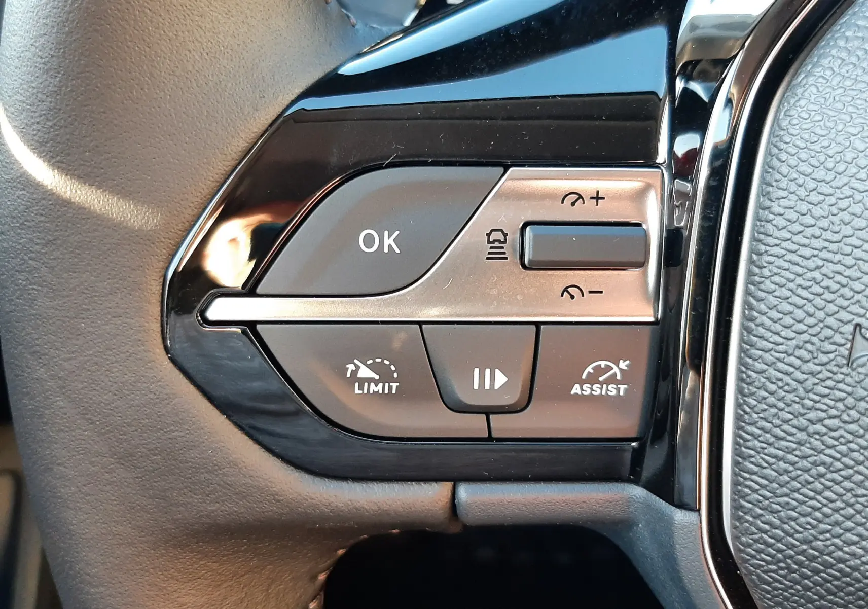 Gros plan sur les commandes à gauche du volant cuir noir de la Peugeot 308 Bleu Obsession 2025, version BlueHDi 130ch.