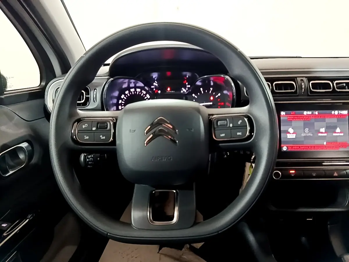 Vue frontale du tableau de bord et volant noir de la Citroën C3 PureTech 83 Shine avec écran tactile et commandes intégrées.