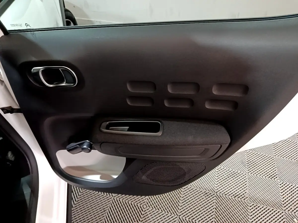Intérieur de la porte côté gauche blanche de la Citroën C3 2023 avec poignée noire et haut-parleur intégré.