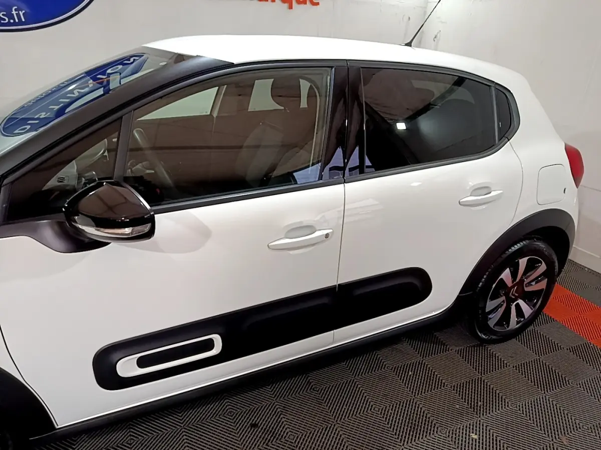 Profil côté gauche d'une Citroën C3 blanche avec protections latérales noires et jantes bicolores modernes