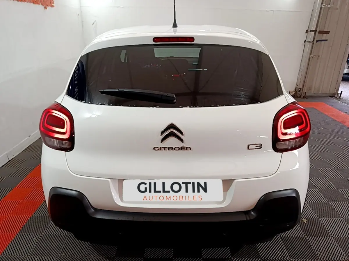 Vue arrière d'une Citroën C3 blanche 2023 avec feux arrière LED et logo centré sur un sol à damier noir et orange.