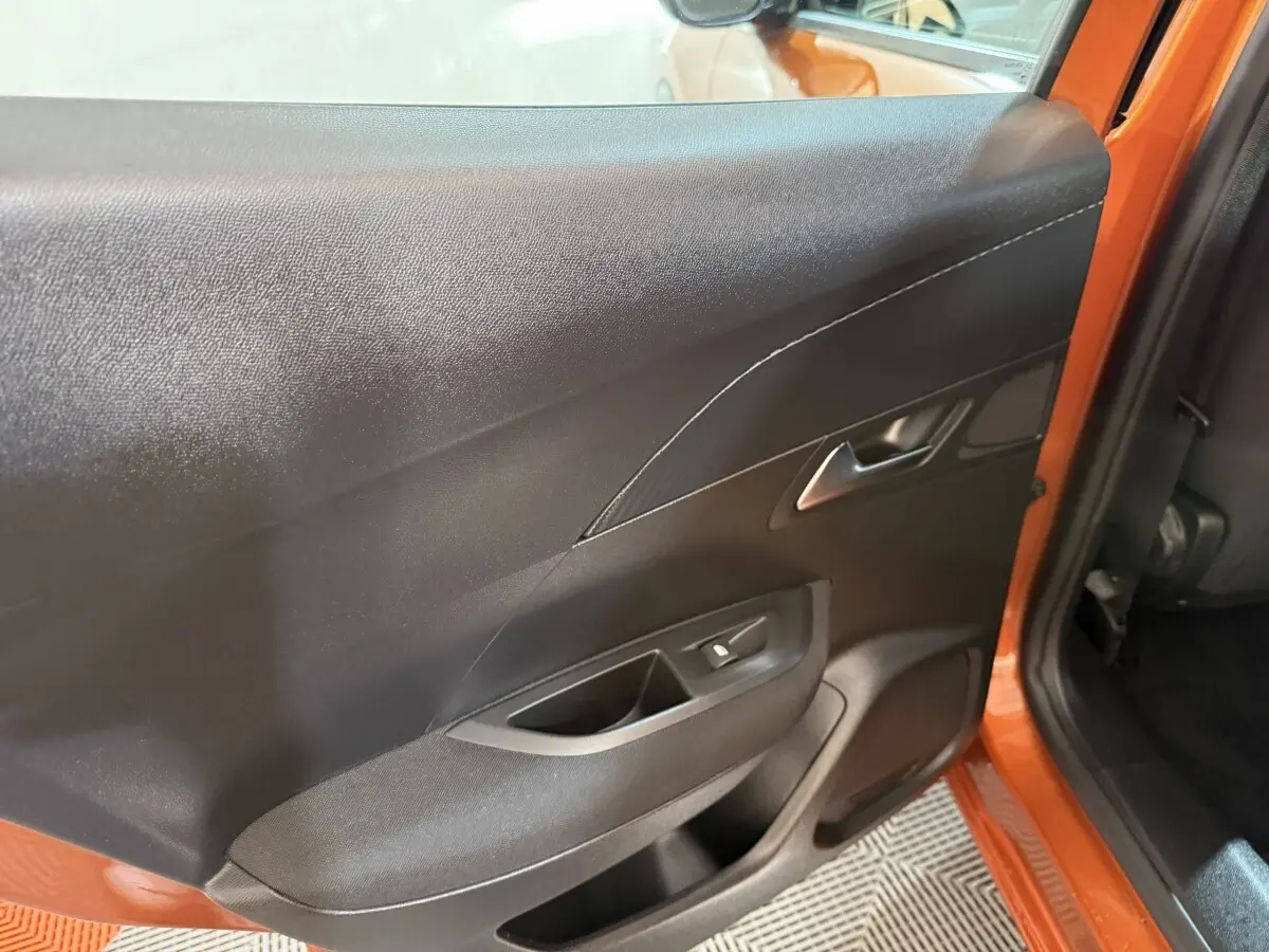 Vue intérieure côté gauche de la porte arrière orange d’un Peugeot 2008 2022 avec commande de lève-vitre.