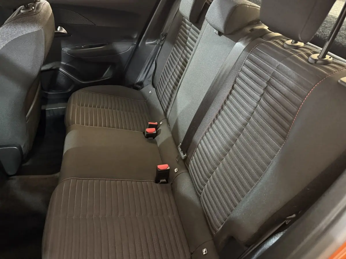 Vue intérieure côté arrière droit montrant la banquette noire du Peugeot 2008 orange, avec ceinture et appuie-têtes visibles.